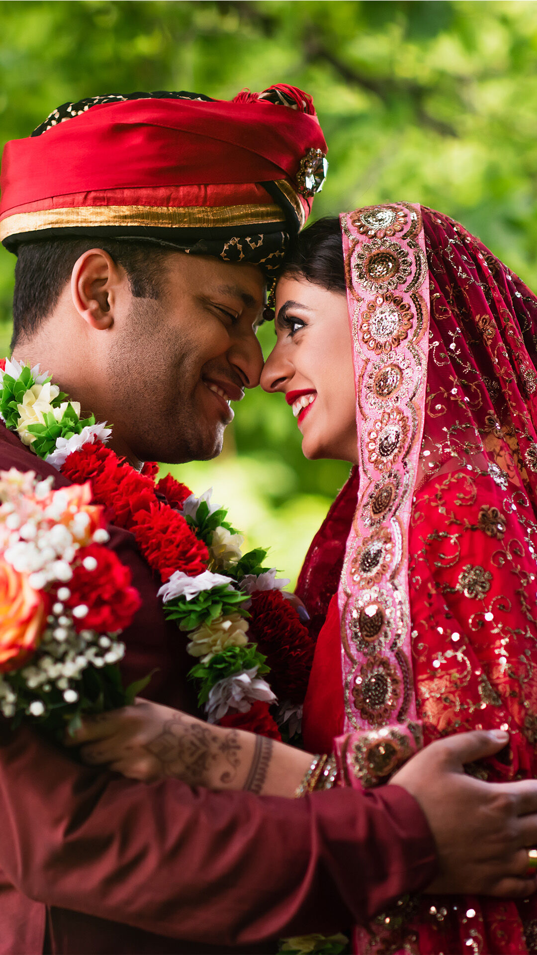 Indian bride and groom wearing varmala (garlands) and holding flowers, joyfully celebrating their wedding ceremony.